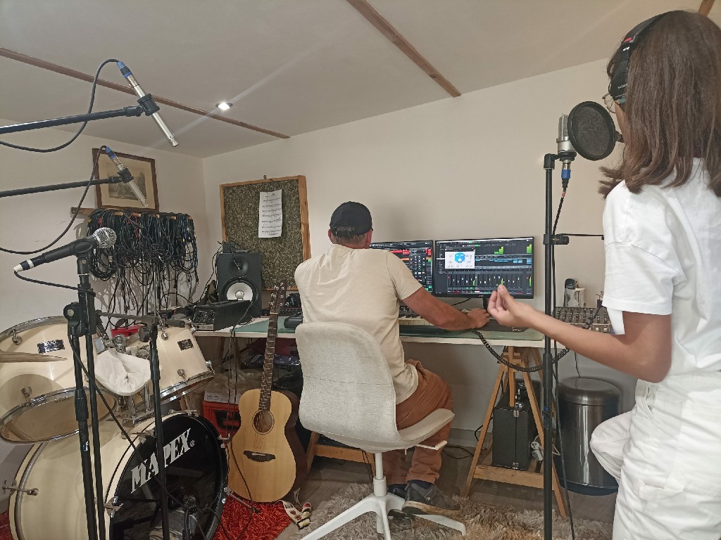 Un ingénieur du son mixe de la musique sur Cubase dans un studio professionnel, avec une chanteuse au premier plan et divers instruments.